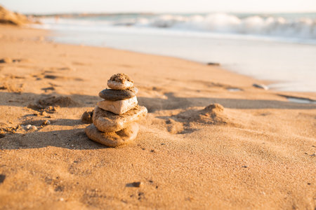 Stack of stones on beach sand over sea background close up. Summer vacation season.の写真素材