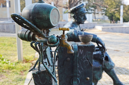 Mosquitofaucet with keg and rested man in cap original benchsculpture in Telavi. Georgiaの写真素材