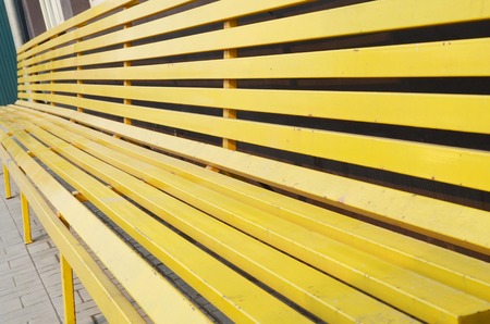 Long wooden yellow bench in the cityの写真素材