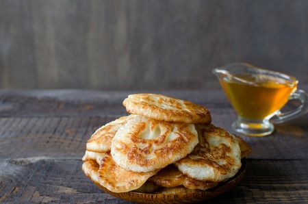 Russian-style fritters and honey on dark wooden background. Empty space