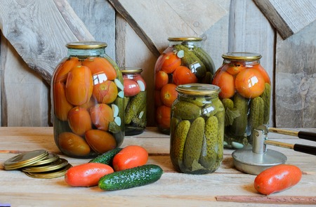 Glass jars with canned tomatoes and cucumbers. Wooden backgroundの写真素材