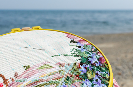 Hoops with unfinished cross stitch on shore of Lake Baikal. Occupation on the beachの写真素材