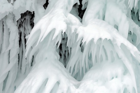 Ice splashes on frozen rocks and stones, formed during freezing of lake