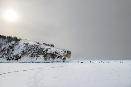 Sunset. Group of travelers goes to West coast of Olkhon Island through Baikal Ice. Winter eveningの写真素材