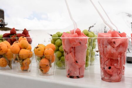 Pieces of fresh fruit in glasses on background of Caucasus Mountains among the snowsの写真素材