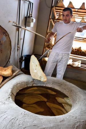 Mtskheta, Georgia - May,06 2019: Man bakes Shotis Puri in tone - stone oven for baking Georgian breadのeditorial素材