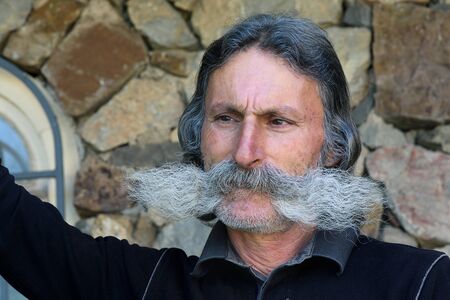 Resident of Khor Virap Monastery with picturesque mustache against background of stone wallのeditorial素材