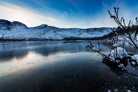 Solar halo in the mountains near a lake covered with ice on a winter eveningの写真素材