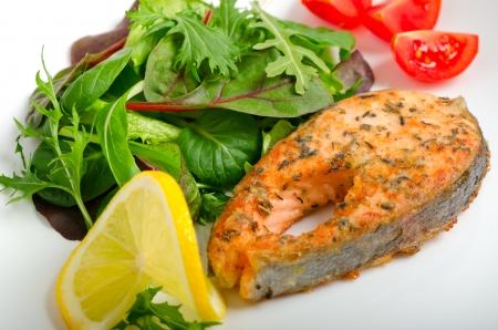 Grilled salmon with mesclun salad, cherry tomatoes and lemonの写真素材