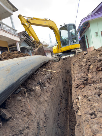 Excavator Digging Trench for Pipeline Installation in Urban Areaの写真素材