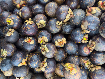 Fresh mangosteens piled together in a vibrant market settingの写真素材