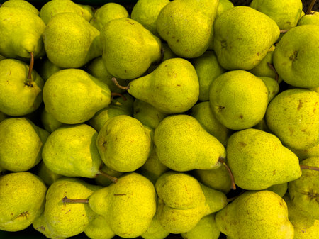 Fresh green ripe pears stacked in abundance at a market stallの写真素材