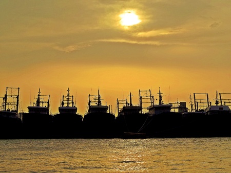 sunset behind clouds and silhouettes of fishing boats, port of Chittagong, Bangladeshの写真素材