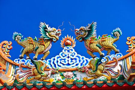 chinese style dragon at temple roof top on blue skyの写真素材