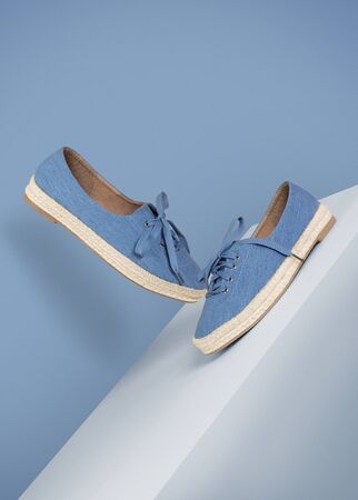 blue sneakers shoes floating on a white box on a blue background side and front view product mood shotの写真素材