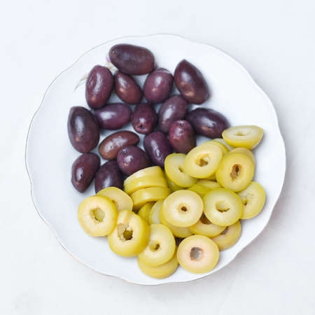 Pickled olives, cucumber, lemon and pepper Homemade organic lightly salted cucumbers Appetizer. Organic, healthy food Eat fresh with a fork Pickled vegetables in plate on the wooden white backgroundの写真素材