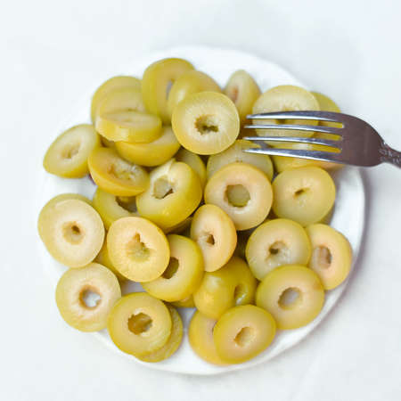 Pickled olives, cucumber, lemon and pepper Homemade organic lightly salted cucumbers Appetizer. Organic, healthy food Eat fresh with a fork Pickled vegetables in plate on the wooden white backgroundの写真素材