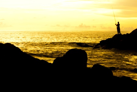 a man is fishing in evening and gold sunset backgroundの写真素材
