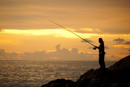 a man is fishing in evening and gold sunset backgroundの写真素材