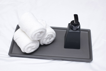 white roll towel and lotion bottle on bedの写真素材
