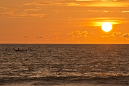 big sun and the boat on the water in sunset timeの写真素材