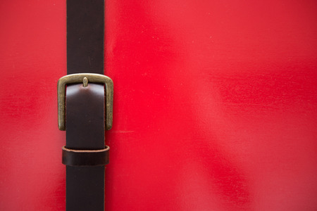 Leather belts on the red wall, accessoriesの写真素材
