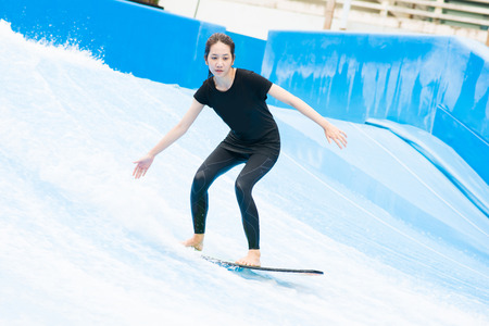 asia girl is playing surf borad with artificial waves house, actionの写真素材