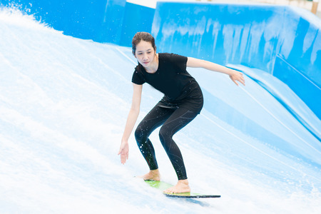 asia girl is playing surf borad with artificial waves house, actionの写真素材