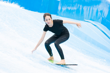 asia girl is playing surf borad with artificial waves house, actionの写真素材