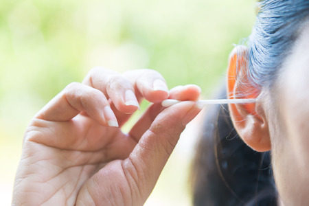 a woman cleaning ear with cotton bud, stickの写真素材