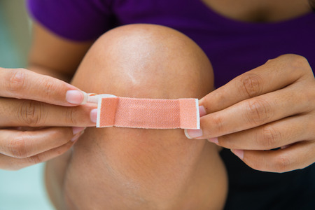 Woman sticking plaster on his knee, accidentの写真素材