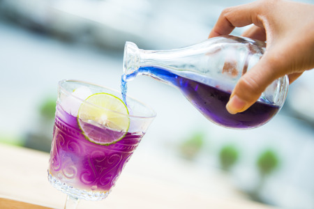 woman's hand pouring pea flower water into a glass, freshの写真素材