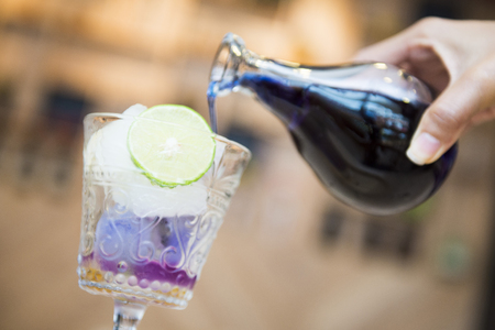 woman's hand pouring pea flower water into a glass, freshの写真素材
