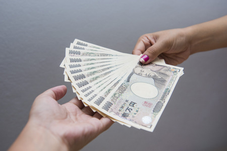 female hand giving japanese money banknotes, yenの写真素材