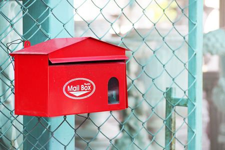 red postbox hanging in front of the fence, letterbox