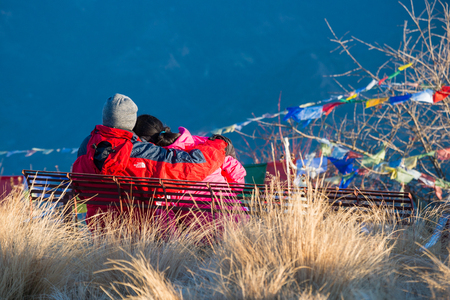 Nepal - 26 Decamber 2016 :: couple are sitting and look the beautiful view at Poon Hill , snow mountainのeditorial素材