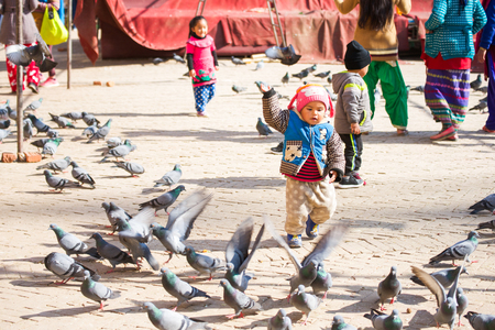 Nepal - 3 January 2017 :: Nepali kid playing with pegion at Boudhanath Stupa , Kathmanduのeditorial素材