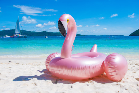Giant inflatable pink flamingo pool float toy on the tropical beach, sea の写真素材