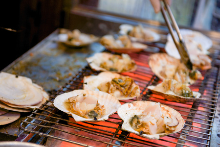 Grilled scallop with the seashell on stove in Kuromon Ichiba Market, Osaka, Japan