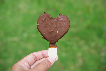 Ice cream chocolate heart in hand with blurry background, dessert