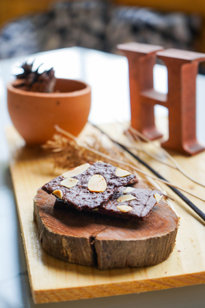 Brownie cracker with almond slides on wooden plate, dessertの写真素材