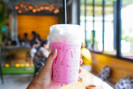 Iced pink milk in hand at coffee shop, beverageの写真素材