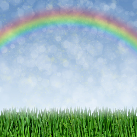 Green grass, blue sky and rainbow as a backgroundの写真素材