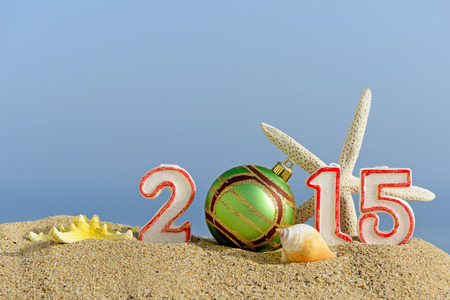 New year 2015 sign with seashells, starfish and christmas ball on a beach sand