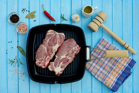 Two pieces of pork meat in a pan and spices for cooking in the grillの写真素材