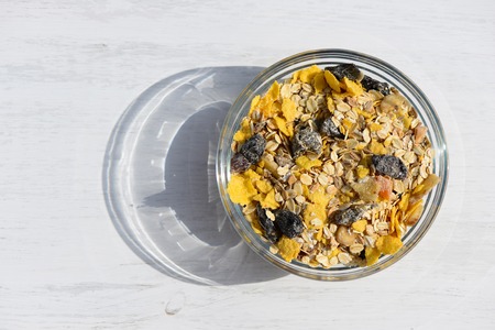 Home-made breakfast muesli with milk on white wooden background