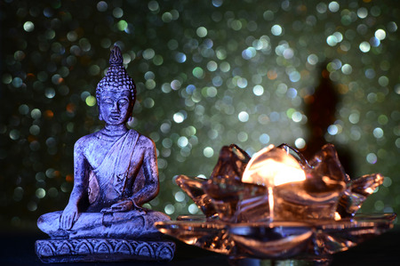 Zen Buddha statue on a bright shiny glitter background with bokehの写真素材