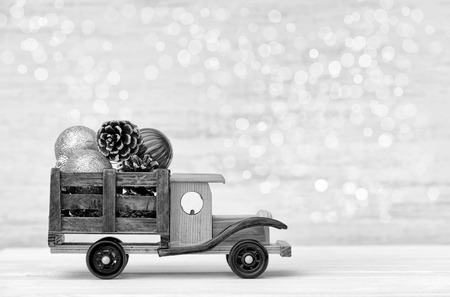 Toy car with Christmas toys on a woden white background with bokeh. Black and white imageの写真素材