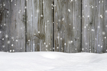 Falling snow on a background of an blurred old wooden barn wallの写真素材