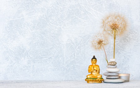 Buddha, pyramid of pebbles, burning candle and dandelion flowers as zen backgroundの写真素材